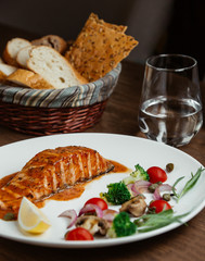 grilled salmon in sauce, served with broccoli, onion, cherry tomatoes, lemon, tarragon