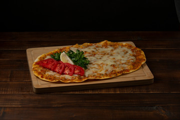 lahmacun italian pizza with minced meat, melted cheese, served with parsley and lemon