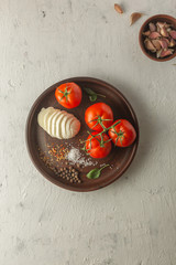 Mozzarella, basil, tomatoes and spices on a brown dish.