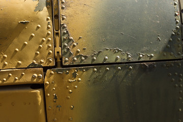 Details of the fuselage of an old aircraft. Old camouflage surface with exfoliated paint and rivets on a military aircraft.