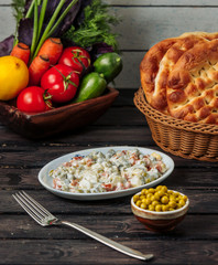 olivier salad in white small platter served with green peas