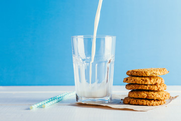 Fresh milk and tasty cookies on a blue background