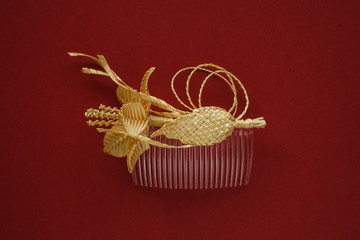 Ornamental hair comb with straw flowers on a red background
