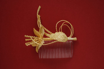 Fototapeta na wymiar Ornamental hair comb with straw flowers on a red background