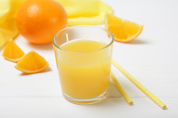 Orange juice in a glass, oranges and orange slices on the table.