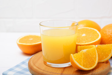Orange juice in a glass, oranges and orange slices on the table.