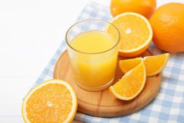 Orange juice in a glass, oranges and orange slices on the table.