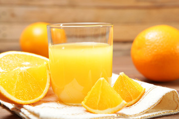Orange juice in a glass, oranges and orange slices on the table.