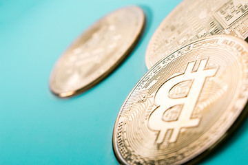 The close up of three gold Bitcoins in plain background.