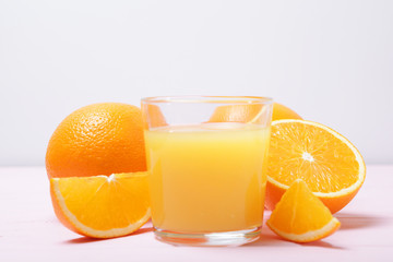 Orange juice in a glass, oranges and orange slices on the table.