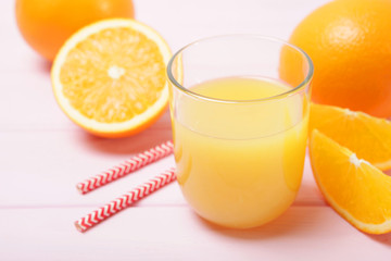 Orange juice in a glass, oranges and orange slices on the table.
