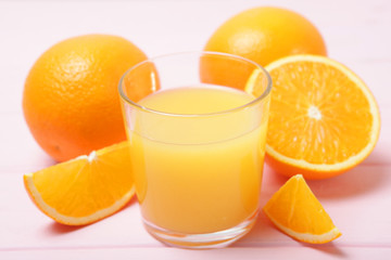 Orange juice in a glass, oranges and orange slices on the table.