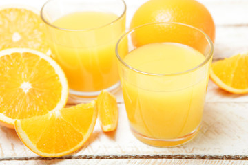 Orange juice in a glass, oranges and orange slices on the table.