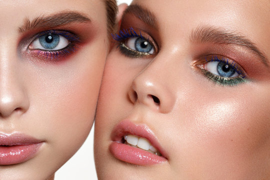 Two young beautiful models cheec to cheek at the photo. A very close up portrait.