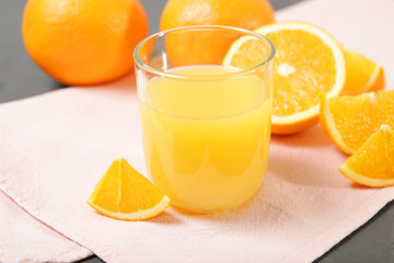 Orange juice in a glass, oranges and orange slices on the table.