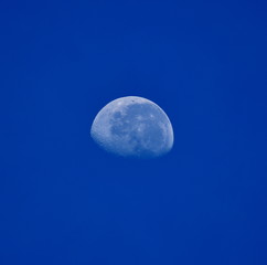 Image of a three quarter moon in front of a blue sky