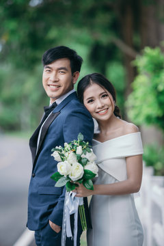 Wedding photo outdoor, Young couples are embracing happily with a green grass background.