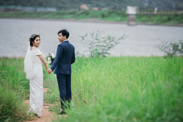 Couples in romantic wedding dresses are enjoying a stroll through the beautiful sunset with a green grass background.