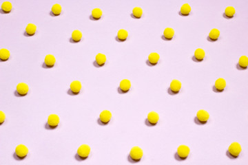 Yellow pompom polka dots pattern on pastel pink background