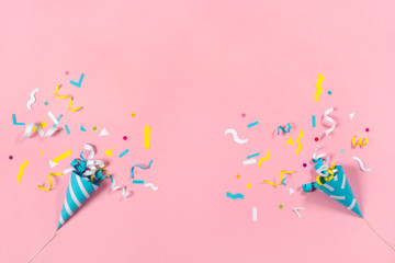 Colorful paper confetti exploding on pastel pink background