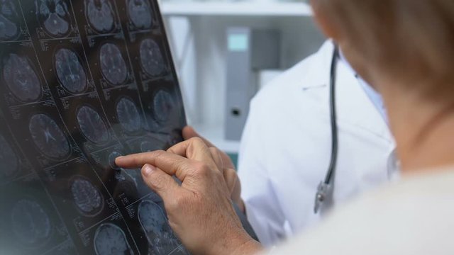 Two doctors looking at x-ray results, discussing patient symptoms and diagnosis