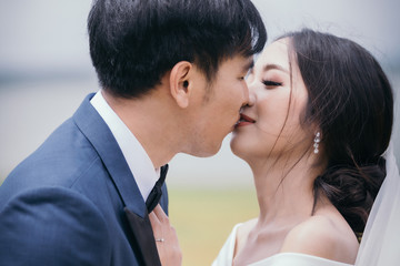 Wedding couple, Handsome groom kisses bride in white dress on the green meadow.