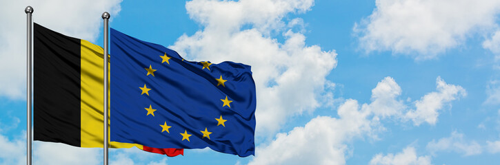 Belgium and European Union flag waving in the wind against white cloudy blue sky together. Diplomacy concept, international relations.