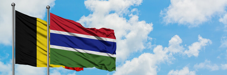 Belgium and Gambia flag waving in the wind against white cloudy blue sky together. Diplomacy concept, international relations.
