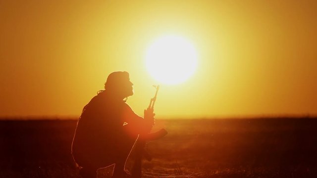 warrior with Kalashnikov at sunset day. fighter is training with a machine gun at sunset.