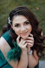 Naklejka premium Beauty fashion portrait. Sexy face of an attractive lady posing. Attractive young girl touching hands face. Photo girl with perfect skin ourdoor. Beautiful woman with long brown curly hair. 
