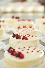 Red cherry on white cake on a table with cakes