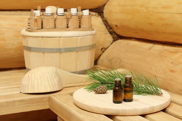 Bottles with healing essential oil for sauna near green pine branch. The concept of natural...