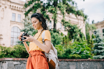 girl holding digital camera near building and trees