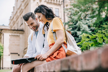 selective focus of happy girl and cheerful man looking at map