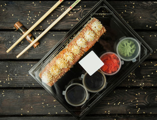 plastic box of shushi rolls for delivery with salmon, sauces, wasabi, ginger