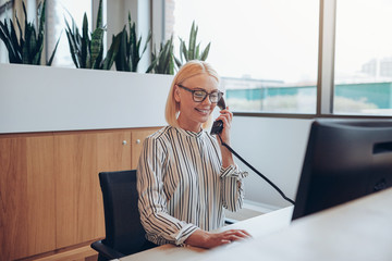 Smiling businesswoman talking to a client over the telephone