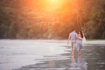 Happy romantic couples strolling and watching the beautiful sunset on the evening beach.