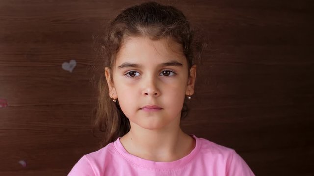 The girl child spits on the palm of the fallen tooth and shows a toothless smile. First lost milk teeth.