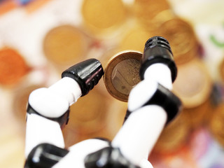 Coin in a robot hand, one euro. Macro of white robotic hand
