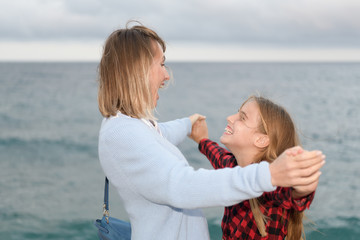 Fototapeta na wymiar Happy mother and daughter holding hands show their affection next to the sea