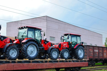 Farm tractors loaded on a freight train. Import/export of the agriculture and farming equipment....