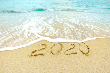 Fototapeta na wymiar New Year 2020 on the sandy shore against the backdrop of sea waves.