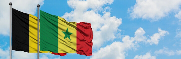 Belgium and Senegal flag waving in the wind against white cloudy blue sky together. Diplomacy concept, international relations.