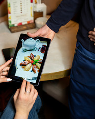 waiter shows dessert menu on tablet to customer at the restaurant