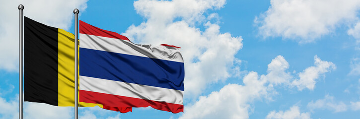 Belgium and Thailand flag waving in the wind against white cloudy blue sky together. Diplomacy concept, international relations.