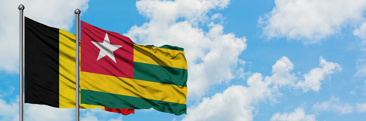 Belgium and Togo flag waving in the wind against white cloudy blue sky together. Diplomacy concept, international relations.