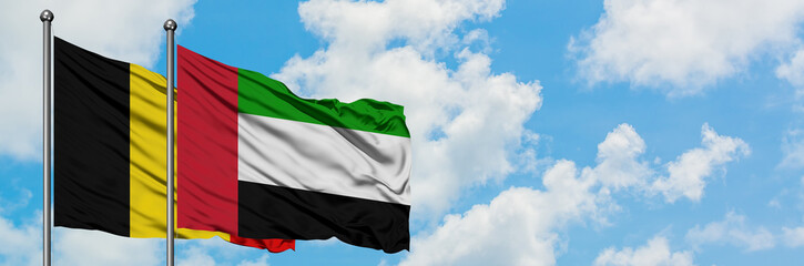Belgium and United Arab Emirates flag waving in the wind against white cloudy blue sky together. Diplomacy concept, international relations.
