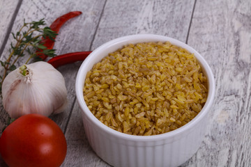 Raw bulgur in the bowl with tomatoes and garlic