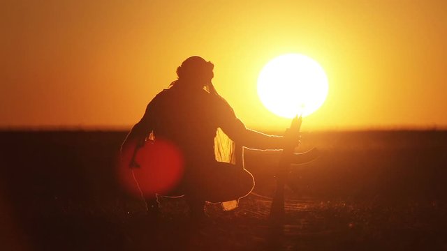 Islamic warrior with Kalashnikov at sunset day. Muslim fighter is training with a machine gun at sunset.