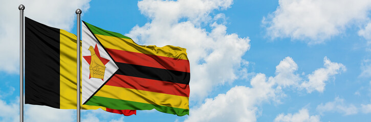Belgium and Zimbabwe flag waving in the wind against white cloudy blue sky together. Diplomacy concept, international relations.